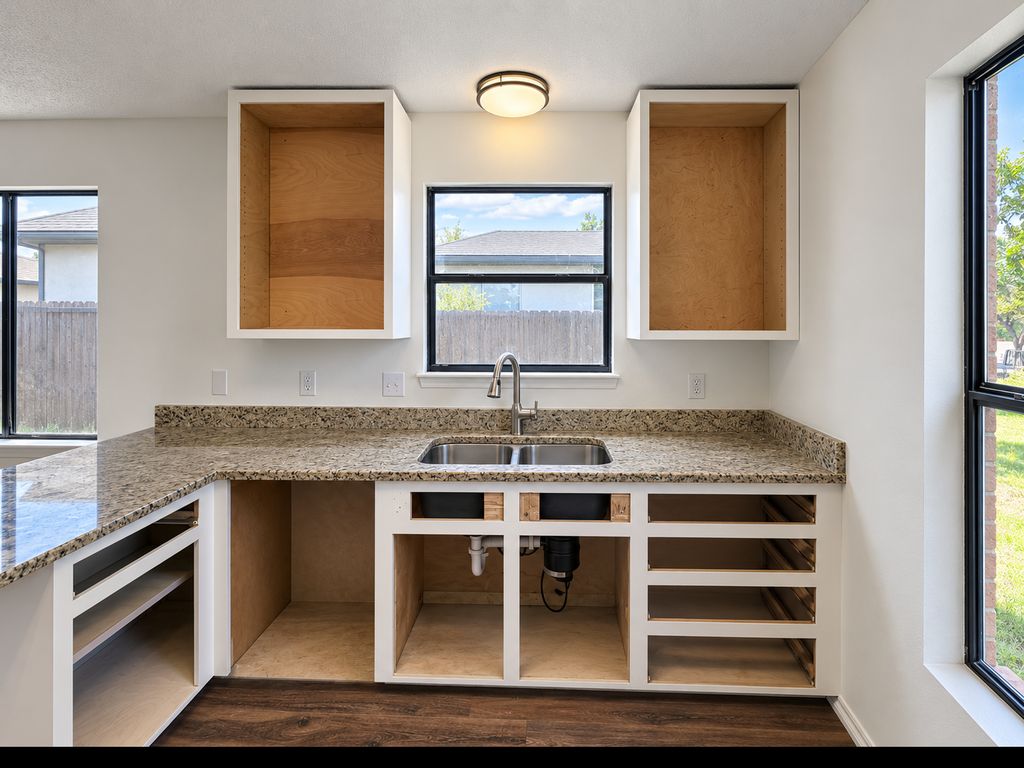 Kitchen during renovation with new upper cabinet boxes installed and existing lower cabinets prepared for refacing